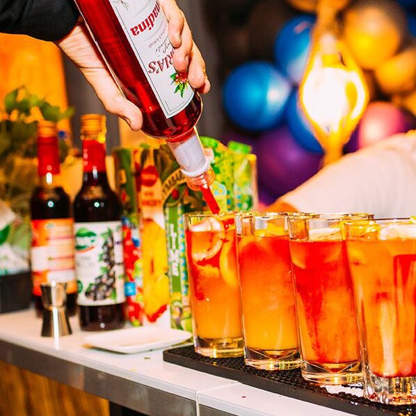 profesjonalny barman serwujący kolroowe drinki dla gości na imprezie w barze